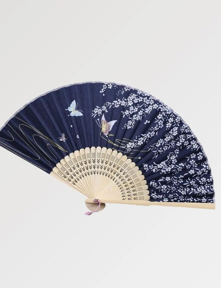 Éventail en bois japonais décoré de papillons lumineux dans un bleu nuit
