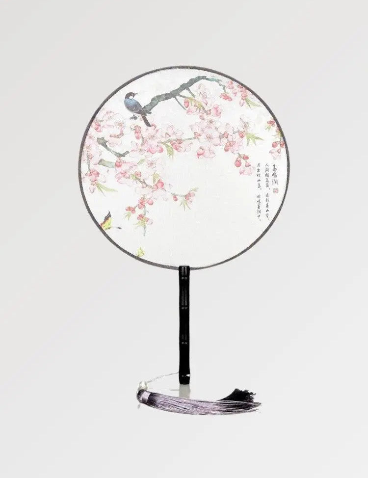 Un éventail japonais rond au tissu blanc dans un motif de fleurs et d'oiseaux