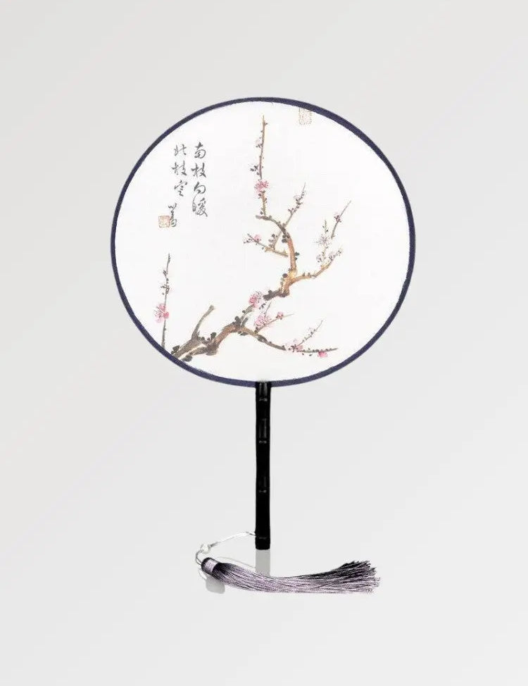Un éventail rond aux écritures japonaises orné d'une branche ou les sakura fleurissent