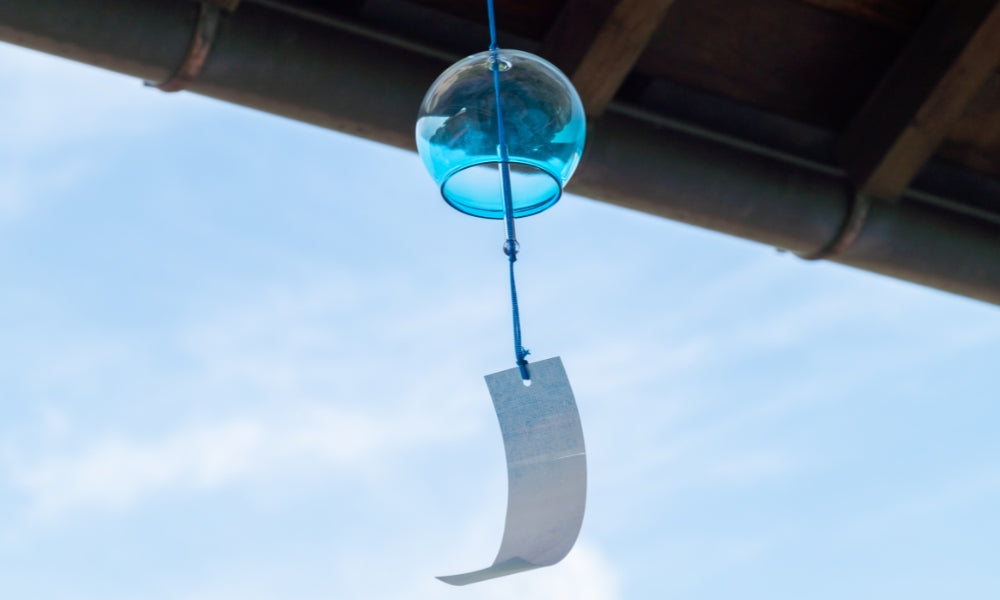 Carillon à vent furin japonais en verre peint à la main, suspendu à l'avant-toit avec sa bandelette de papier tanzaku — le son de l'été japonais