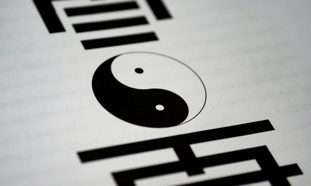 Le symbole yin et yang (taijitu) noir et blanc imprimé sur une page entourée de trigrammes du Yi Jing, représentant la philosophie des opposés complémentaires