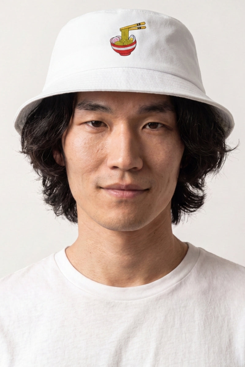 Collection bobs streetwear : homme portant un bob en coton blanc brodé d'un bol de ramen et de baguettes, esprit streetwear japonais