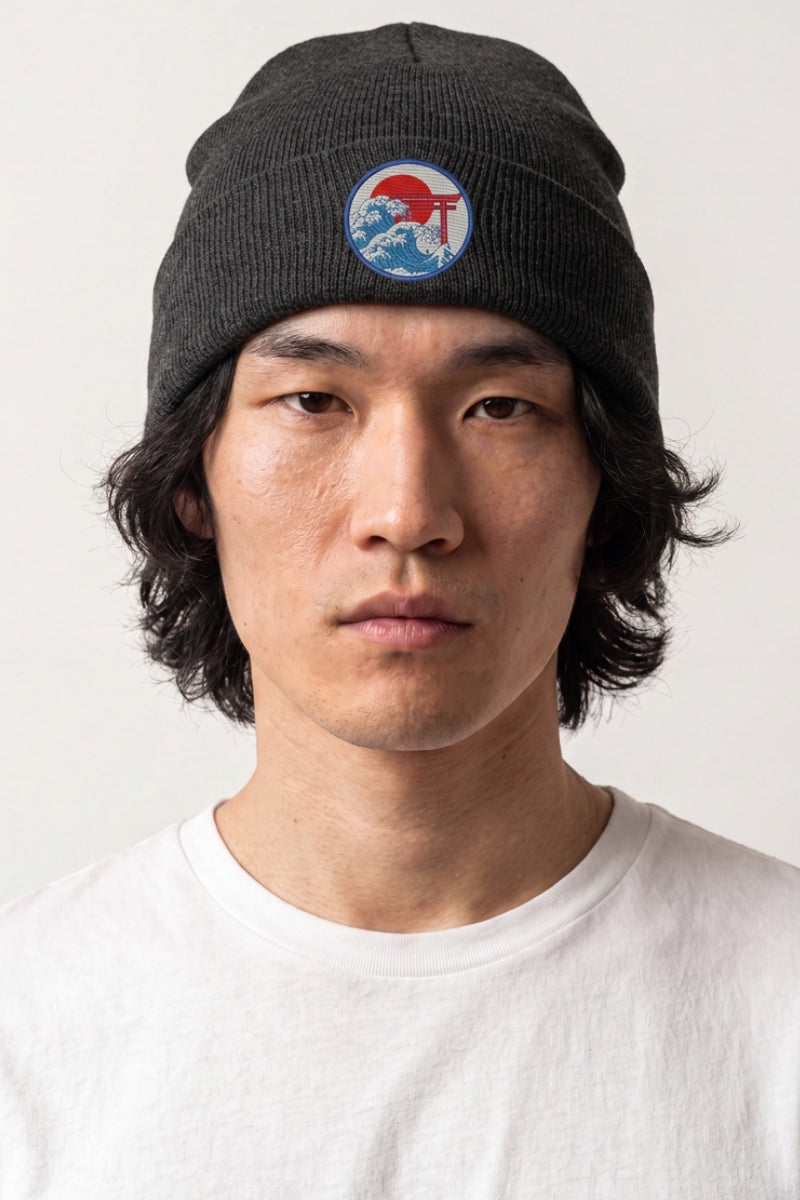 Collection bonnets streetwear : homme portant un bonnet en maille côtelée anthracite à écusson brodé torii, vague et soleil rouge