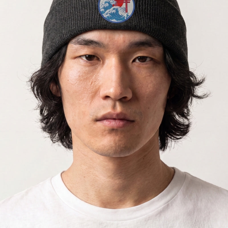 Collection bonnets streetwear : homme portant un bonnet en maille côtelée anthracite à écusson brodé torii, vague et soleil rouge