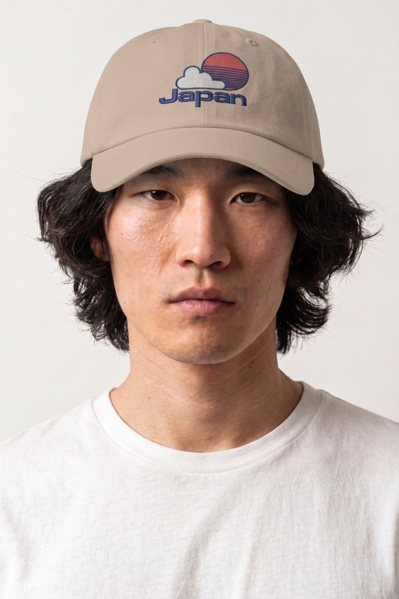 Collection casquettes japonaises : homme portant une casquette beige brodée d'un soleil levant, d'un nuage et d'un lettrage bleu et rouge