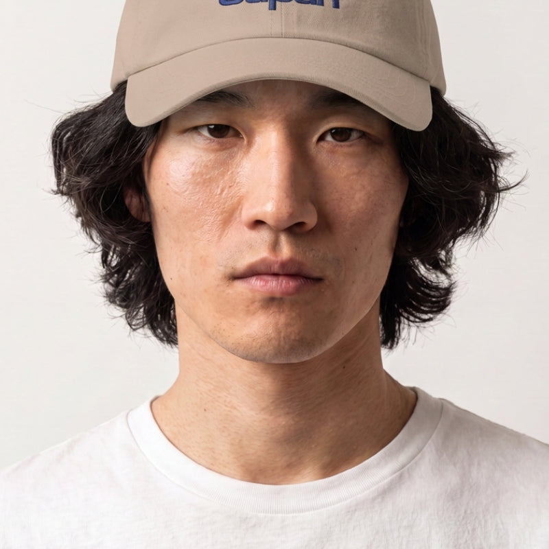 Collection casquettes japonaises : homme portant une casquette beige brodée d'un soleil levant, d'un nuage et d'un lettrage bleu et rouge