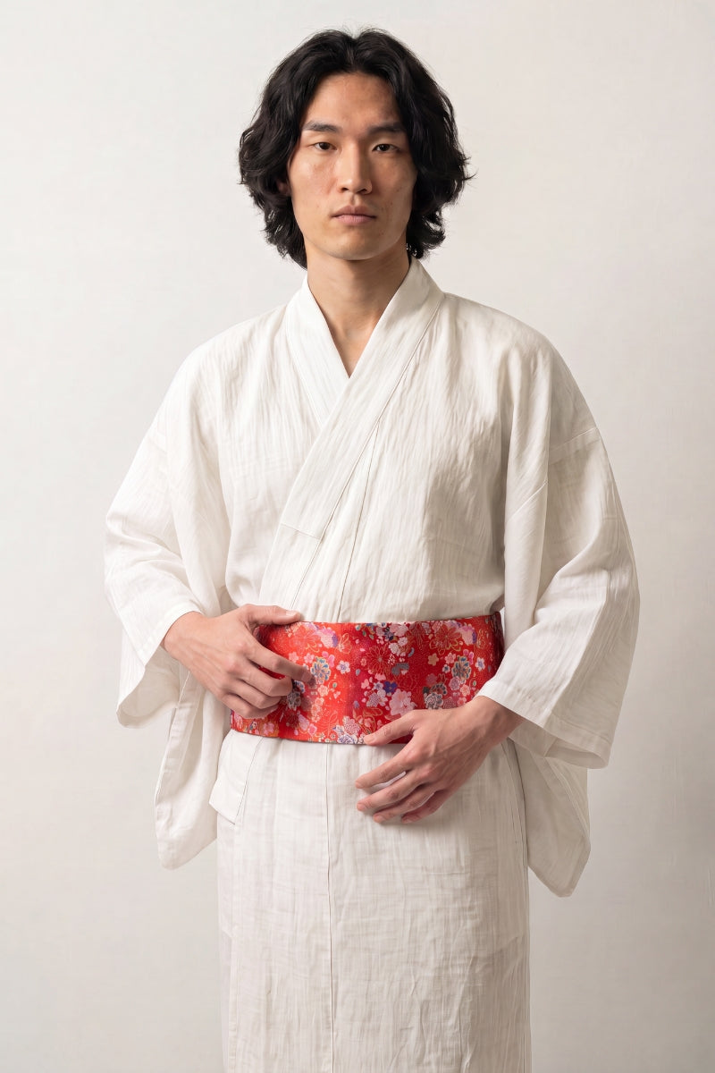 Collection ceintures obi : homme en kimono de lin blanc portant une ceinture obi rouge brochée de fleurs roses, blanches et bleues