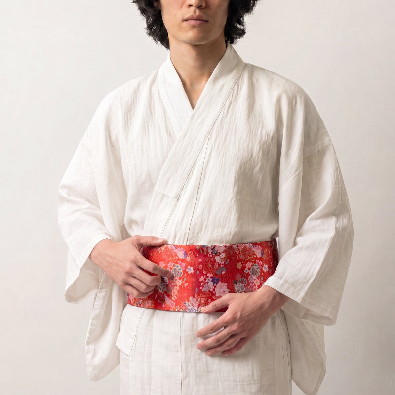 Collection ceintures obi : homme en kimono de lin blanc portant une ceinture obi rouge brochée de fleurs roses, blanches et bleues