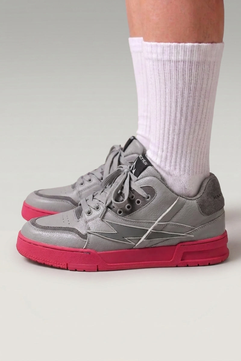 Baskets chunky 'Inazuma' coloris rose — tige blanc et gris posée sur une semelle monochrome vive, portées avec chaussettes blanches sur fond studio gris