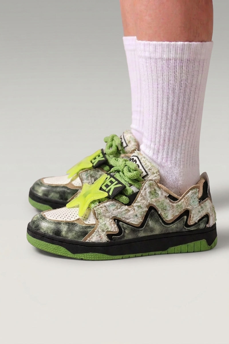 Baskets basses 'Kasumi' coloris noir — graffiti peint sur toute la tige, semelle teintée assortie, portées avec chaussettes blanches sur fond studio gris