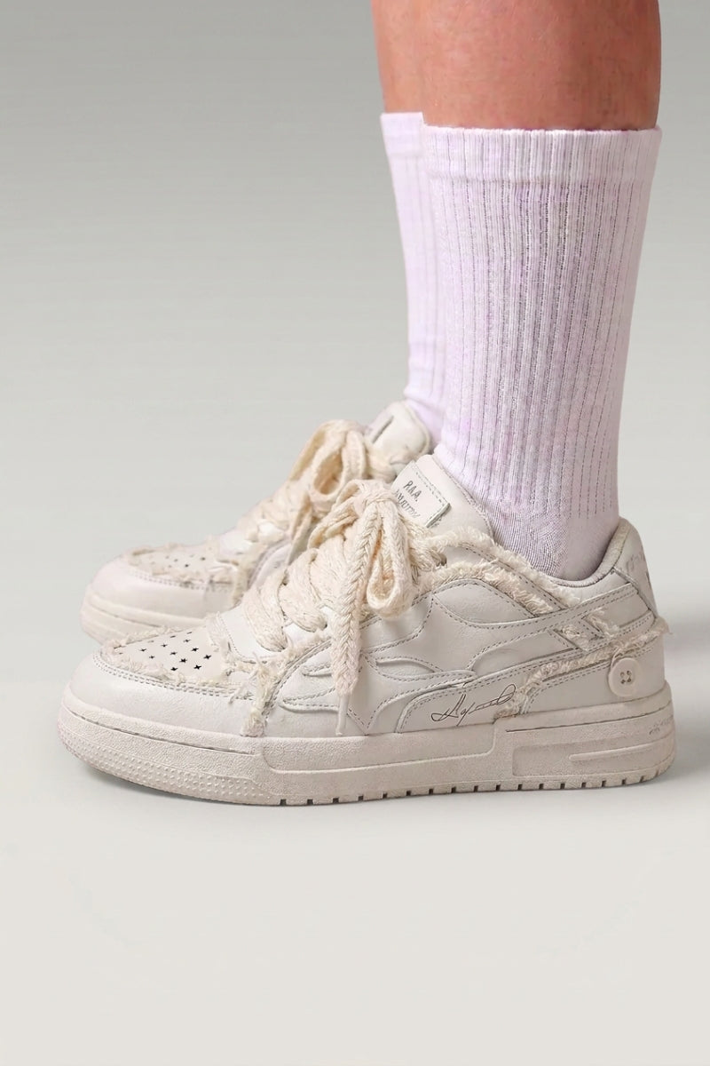 Baskets basses 'Seiryu' coloris blanc — toile délavée à motif floral fondu, semelle cupsole crème, portées avec chaussettes blanches sur fond studio gris