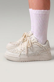 Baskets basses 'Seiryu' coloris blanc — toile délavée à motif floral fondu, semelle cupsole crème, portées avec chaussettes blanches sur fond studio gris
