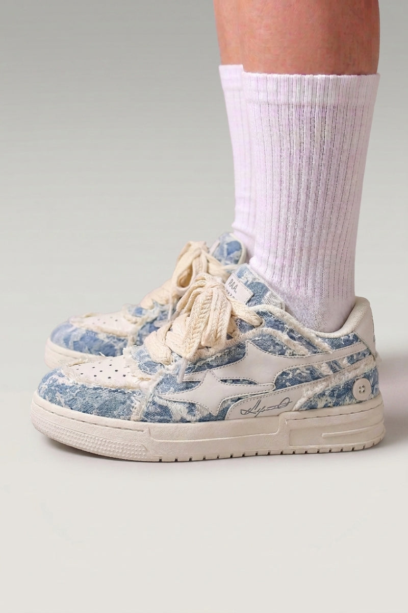 Baskets basses 'Seiryu' coloris bleu — toile délavée à motif floral fondu, semelle cupsole crème, portées avec chaussettes blanches sur fond studio gris