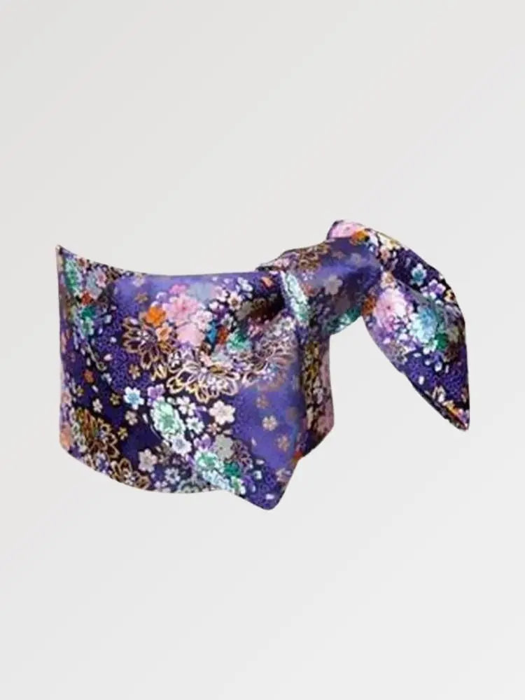 Ceinture obi 'Nadeshiko' nouée sur un buste de mannequin, vue de trois quarts — fond violet profond couvert de fleurs polychromes rehaussées d'or