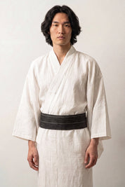 Ceinture obi 'Hikoma' portée à la taille sur un kimono blanc par un mannequin homme — vert sombre presque noir, fines rayures verticales dans le tissage