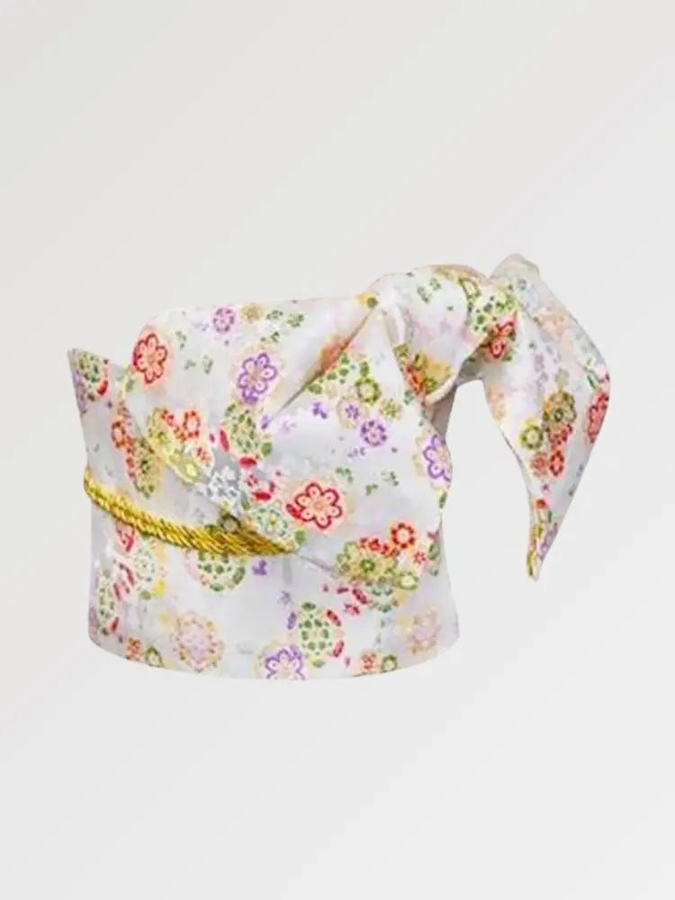 Ceinture obi 'Ume' nouée sur un buste de mannequin, vue de trois quarts — fond blanc à semis de fleurs multicolores, cordon doré en rappel