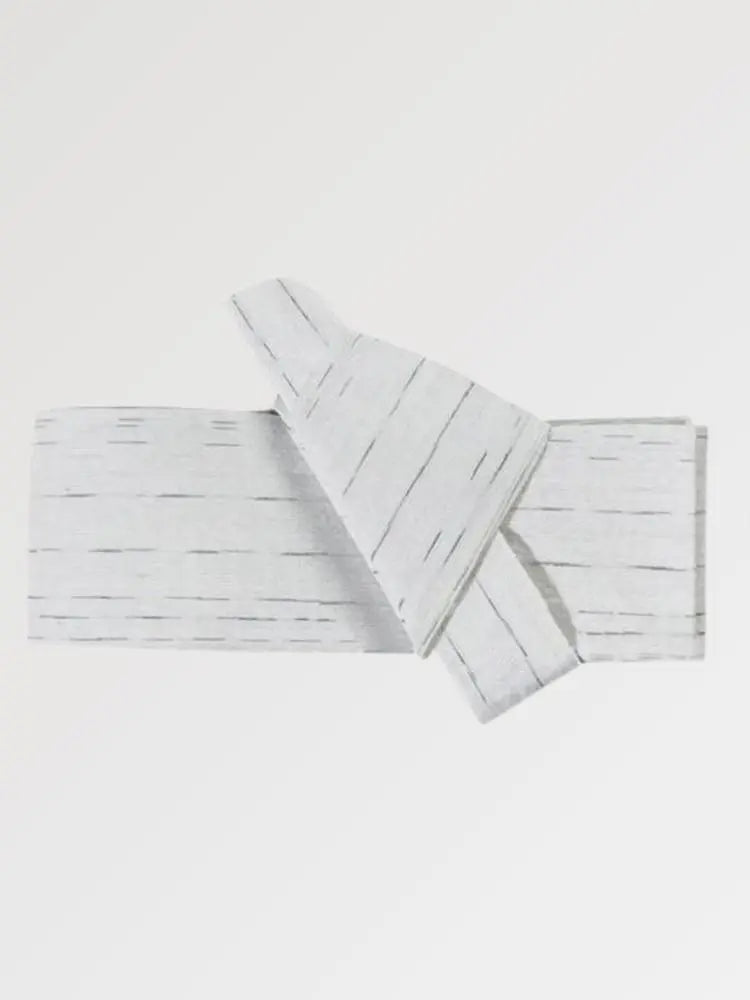 Ceinture obi 'Sakemi' pliée à plat sur fond gris, extrémités repliées l'une sur l'autre — gris très clair strié de traits blancs irréguliers