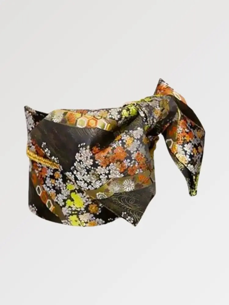 Ceinture obi 'Koshiko' nouée sur un buste de mannequin, vue de trois quarts — brocart sombre à chrysanthèmes orange et dorés sur fond de feuillage