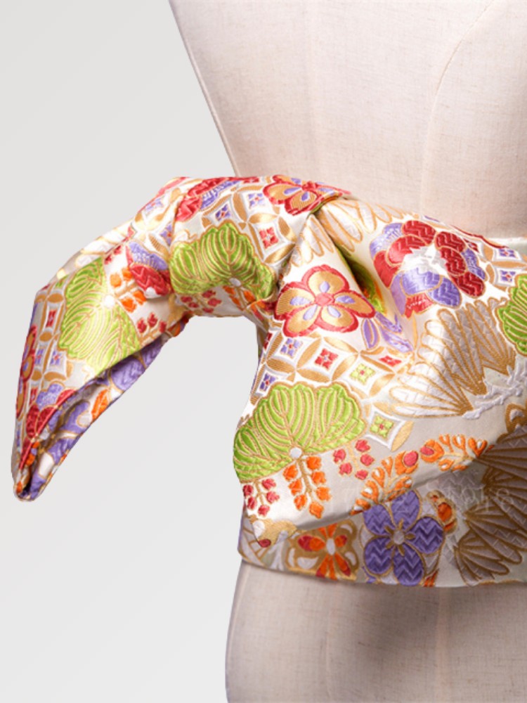 Gros plan du nœud de la ceinture obi 'Kaneshon' sur un buste de mannequin — brocart pastel à grandes fleurs roses, vertes et violettes