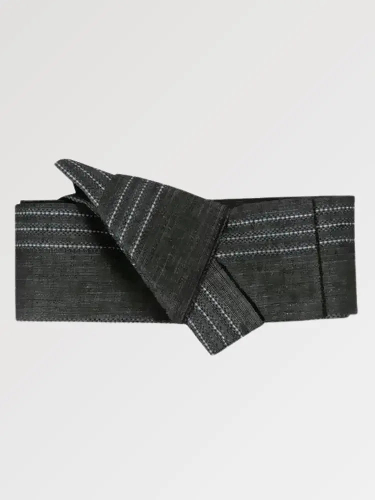 Ceinture obi 'Himeji' pliée à plat sur fond gris, extrémités repliées l'une sur l'autre — gris anthracite rayé de traits blancs discontinus
