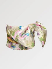 Ceinture obi 'Sakura' nouée sur un buste de mannequin, vue de trois quarts — brocart vert pâle et doré semé de fleurs roses et de grues