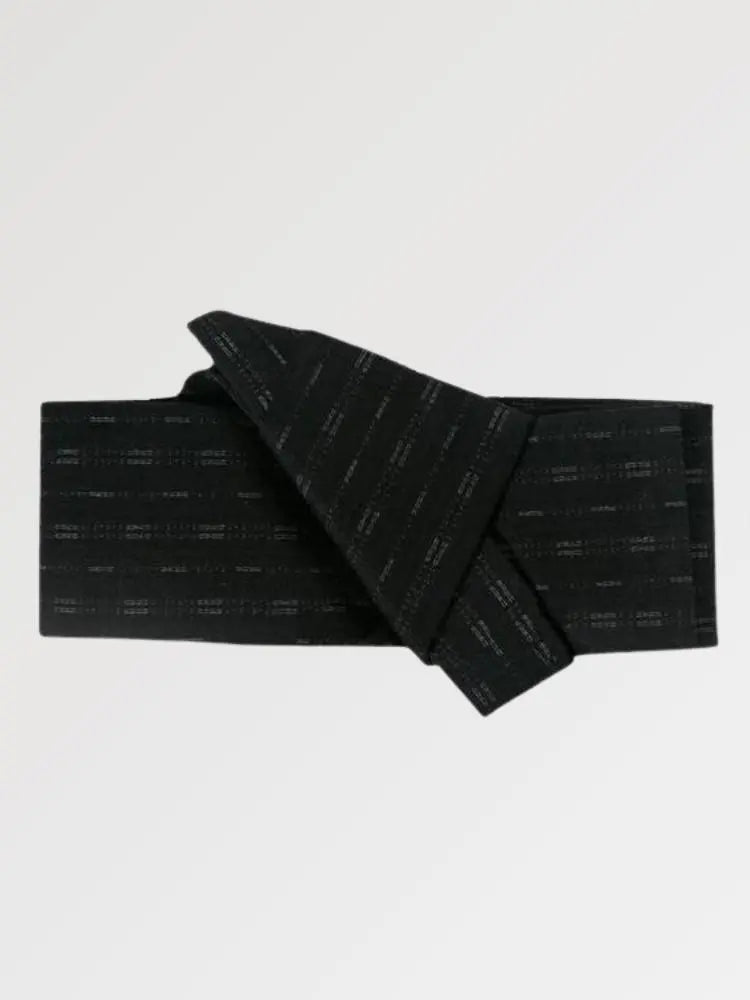 Ceinture obi 'Osaka' pliée à plat sur fond gris, extrémités repliées l'une sur l'autre — noir semé de courts traits clairs disposés en lignes