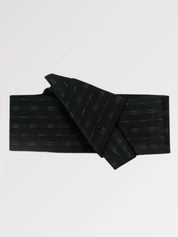Ceinture obi 'Osaka' pliée à plat sur fond gris, extrémités repliées l'une sur l'autre — noir semé de courts traits clairs disposés en lignes