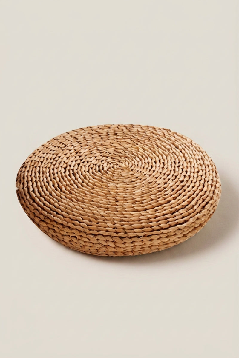 Coussin japonais 'Futon' — zabuton rond en paille tressée à galette épaisse et surface légèrement bombée, paille brune foncée, photo produit sur fond beige