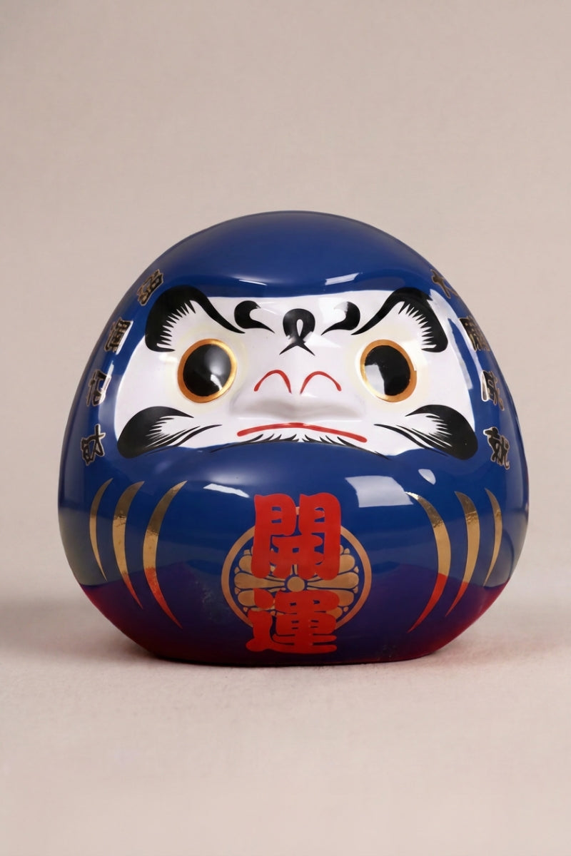 Daruma bleu océan en céramique posé sur fond beige — figurine ronde de 11 cm au kanji 海, yeux vierges pour le rite du vœu