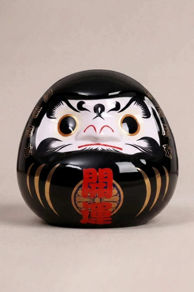 Daruma noir ombre en céramique posé sur fond beige — figurine ronde de 11 cm au kanji 影, yeux vierges pour le rite du vœu