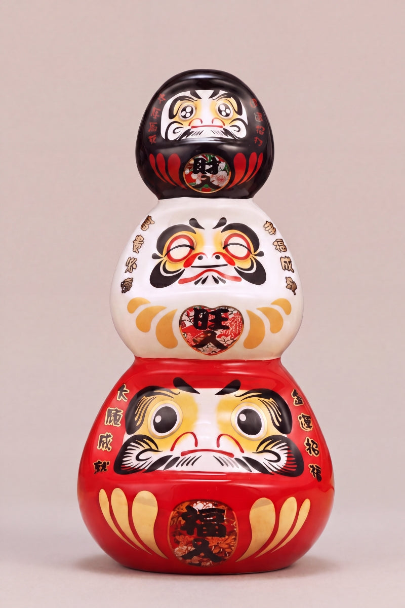 Daruma triple en céramique posé sur fond beige — figurine ronde de 11 cm au kanji 三福, yeux vierges pour le rite du vœu