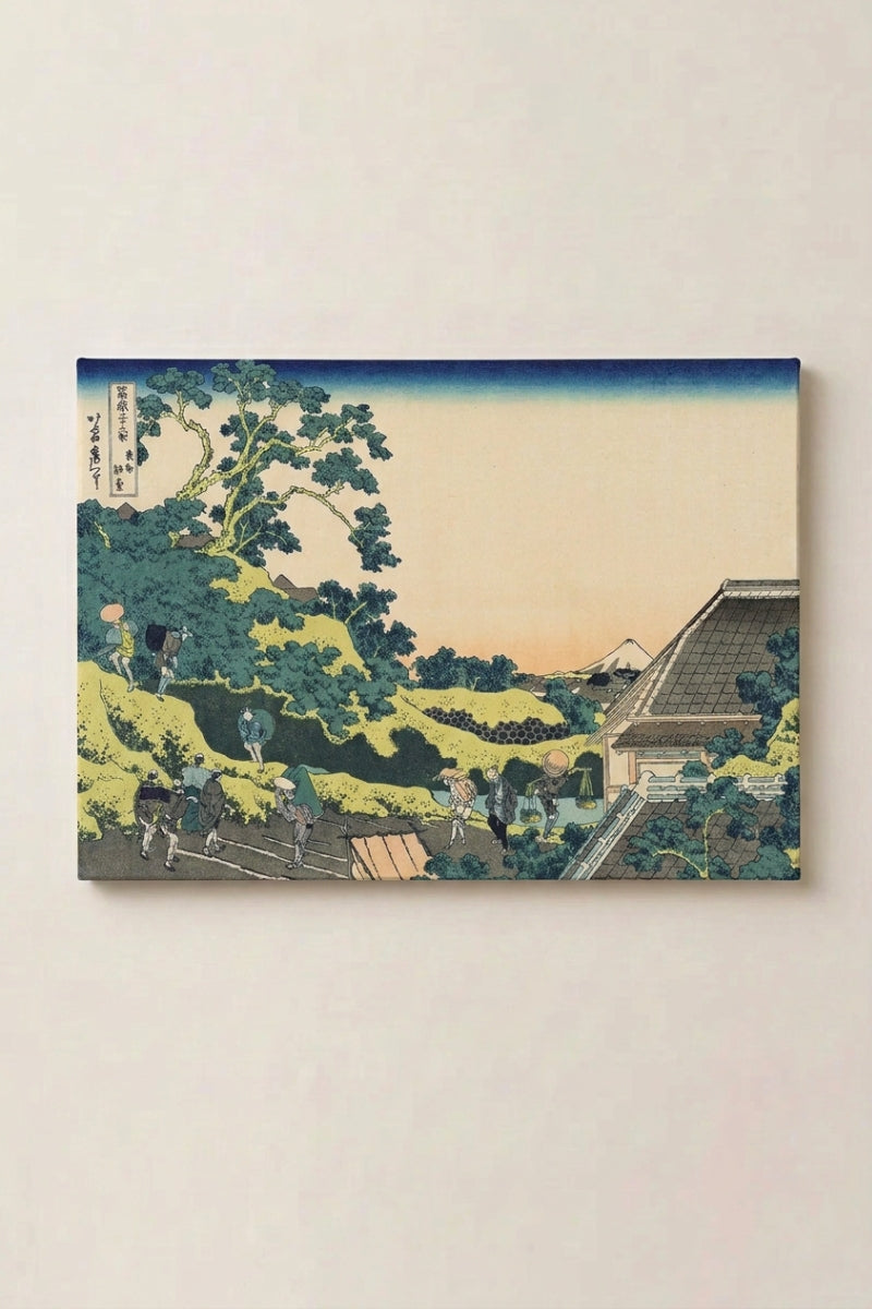 Estampe japonaise 'Shukakku' présentée en panneau encadré sur un mur beige — pente verte plantée d'arbres et toiture d'un pavillon, mont Fuji derrière la crête
