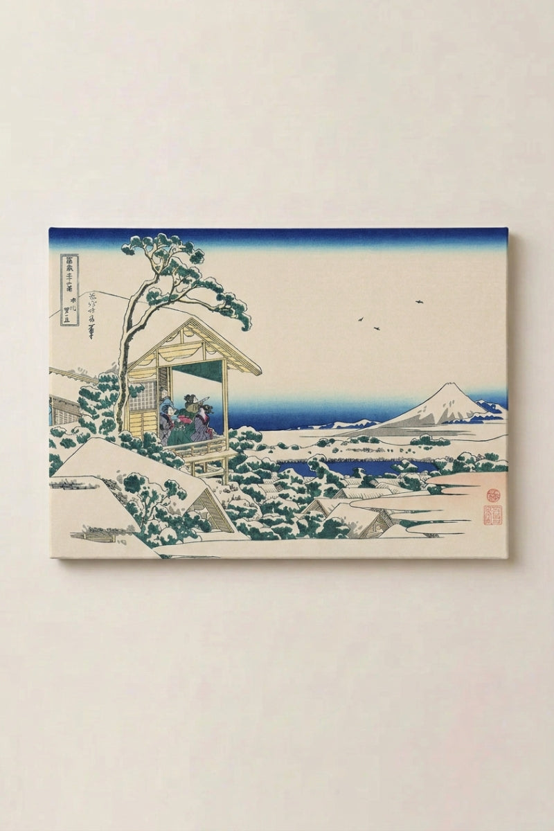 Estampe japonaise 'Ikube' présentée en panneau encadré sur un mur beige — maison de thé sous la neige, toit et pins alourdis de blanc, mont Fuji enneigé au loin