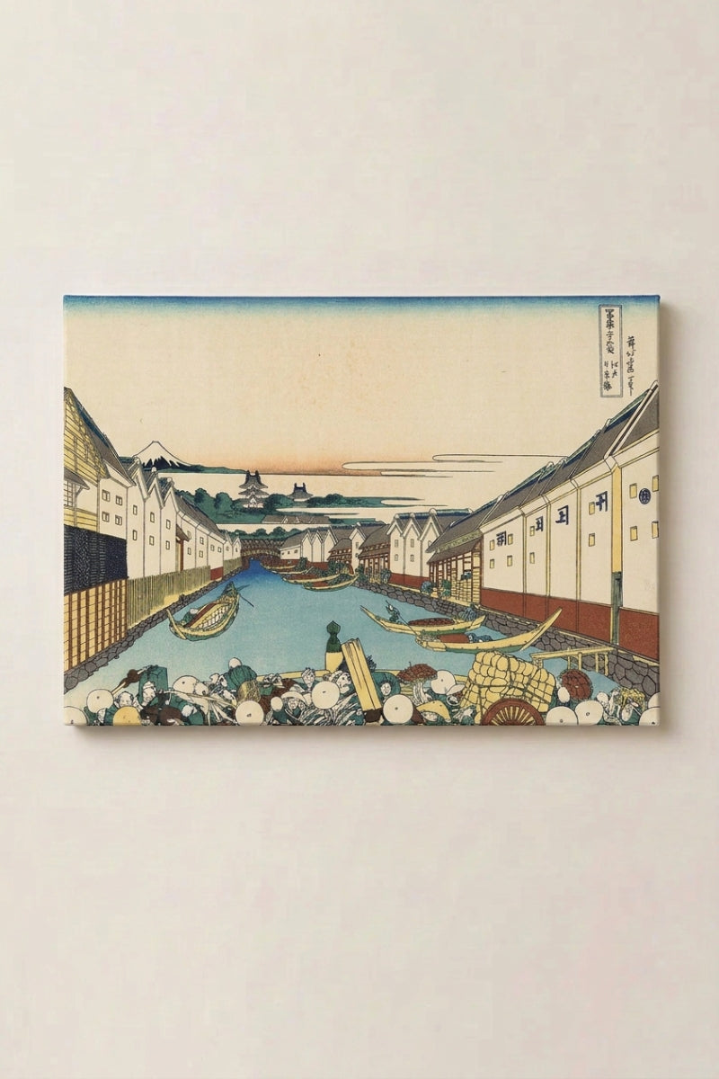 Estampe japonaise 'Onikawa' en panneau encadré sur mur beige — rue de marchands bordée d'entrepôts blancs le long d'un canal encombré de barques, Fuji au loin