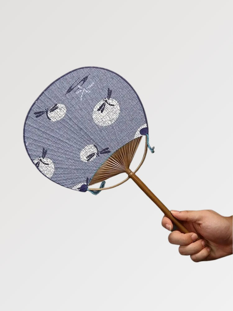 Éventail uchiwa japonais 'Shoji' modèle 9, tenu en main — fond bleu pâle à petits motifs blancs de lapins, manche en bambou
