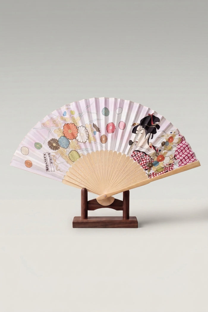 Éventail pliant japonais 'Tsushima' ouvert sur son support — geisha en estampe ukiyo-e et chrysanthèmes sur feuille lilas très pâle