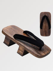 Paire de geta 'Iwakura' vue de trois quarts — socle en bois foncé à deux dents, lanière noire unie, dessous visible