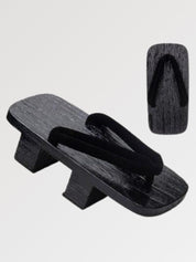 Paire de geta 'Hekinan' vue de trois quarts — socle en bois noirci à deux dents, lanière noire mate assortie au socle, dessous visible