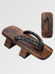 Paire de geta 'Okazaki' vue de trois quarts — socle en bois foncé à deux dents, lanière kaki à motif discret, dessous visible