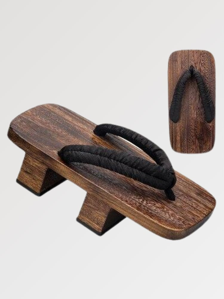 Paire de geta 'Toyohashi' vue de trois quarts — socle en bois foncé à deux dents, lanière noire épaisse et rembourrée, dessous visible