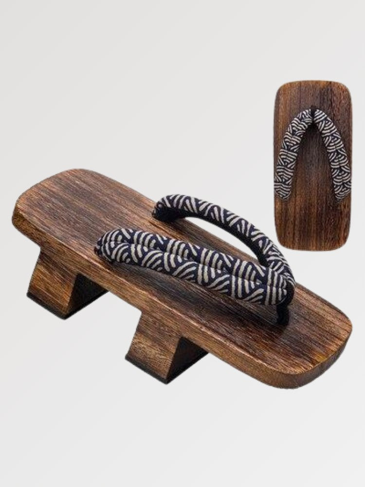 Paire de geta 'Seigaiha' vue de trois quarts — socle en bois foncé à deux dents, lanière à motif de vagues seigaiha noir et blanc, dessous visible