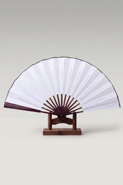 Grand éventail pliant japonais 'Kisho' ouvert sur son support — feuille blanche à liseré foncé et large monture apparente à lames espacées