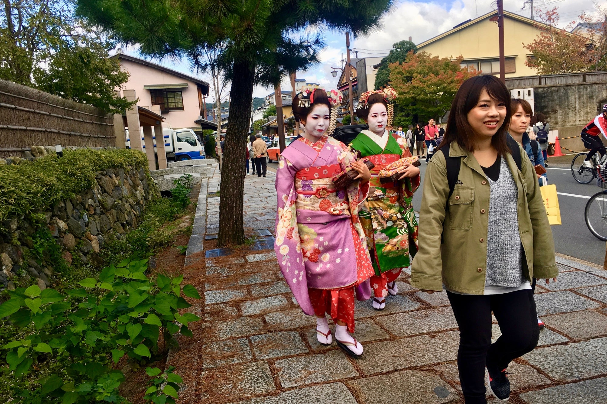 Deux maiko vêtues de kimonos colorés marchent dans une rue de Kyoto, illustrant l’élégance et le patrimoine culturel du Japon.