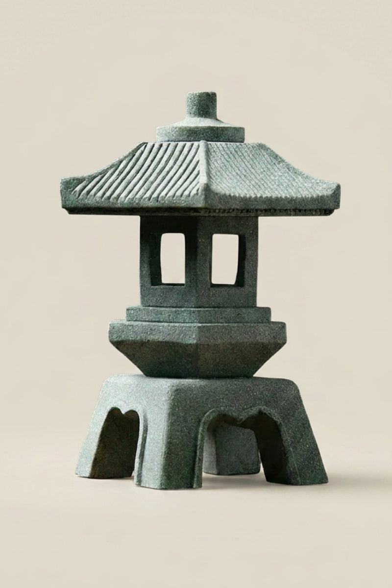 Lanterne japonaise — lanterne de pierre vert-de-gris à toit strié en pente, corps hexagonal percé et pieds en arcades, photo produit sur fond beige uni