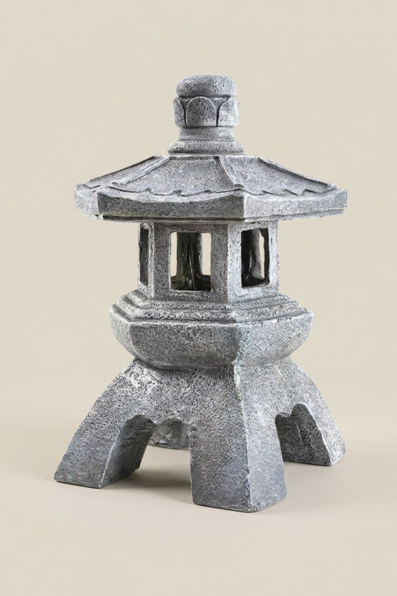 Lanterne japonaise — lanterne d'extérieur en pierre grise à toit hexagonal étagé, fenêtres à croisillons et pieds arqués, photo produit sur fond beige uni