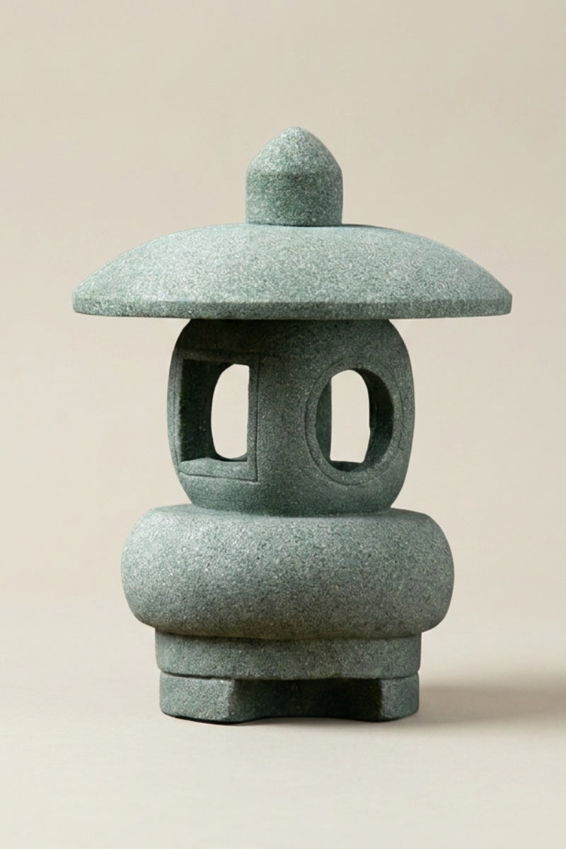 Lanterne japonaise — lanterne de jardin en pierre verte aux formes arrondies, larges ouvertures ovales et base bombée, photo produit sur fond beige uni