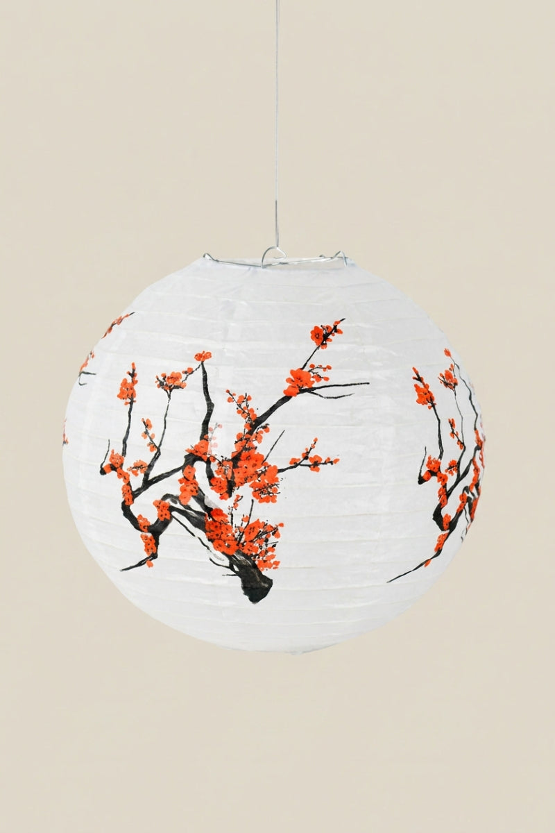 Lanterne japonaise coloris sakura — lanterne boule en papier blanc peinte de branches de prunier aux fleurs rouge orangé, suspendue à un fil sur fond beige uni