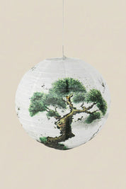 Lanterne japonaise coloris arbre — lanterne boule en papier blanc à pin noueux peint à l'encre verte et noire, suspendue à un fil sur fond beige uni