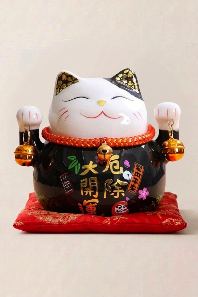Maneki neko tirelire 'Black' en céramique — chat noir laqué à décor doré et plaque calligraphiée, les deux pattes levées, sur un coussin rouge