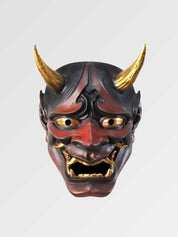 Masque hannya rouge présenté de face sur fond gris uni — démon rouge et noir aux cornes dorées, crocs blancs et regard cerné d'or